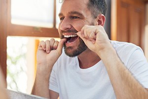 Man smiling while flossing teeth