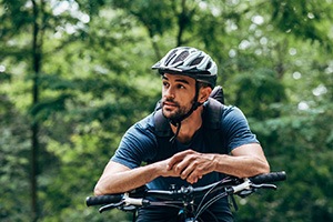 Man with helmet riding bike outside