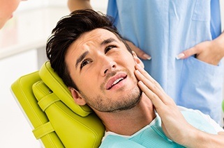 Man in dental chair holding jaw