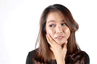 Woman touching her face, has questions about TMJ/TMD