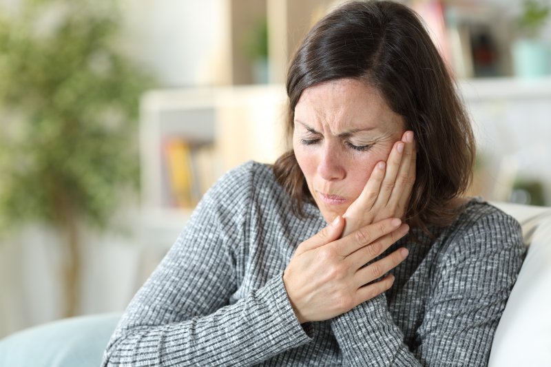 Woman with TMD rubbing her jaw