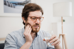 Man with painful toothache rubbing his cheek