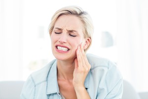 Woman on a couch with pain due to toothache