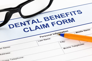 Pen and glasses on top of dental benefits claim form