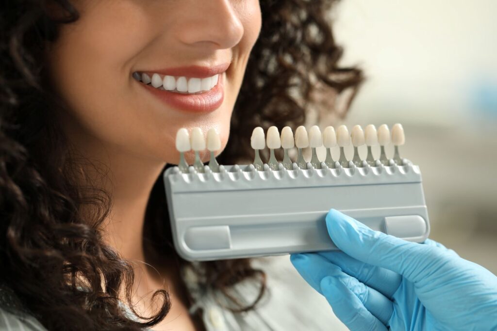 A woman choosing the shade of her veneers at the dentist